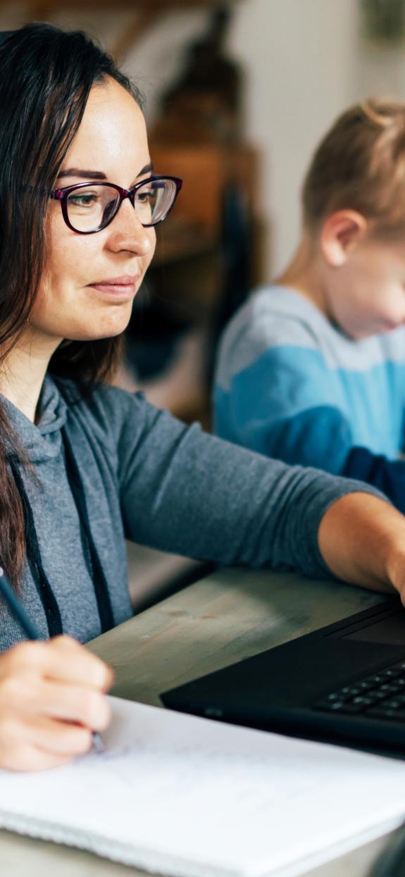 Parent looking at laptop while child draws