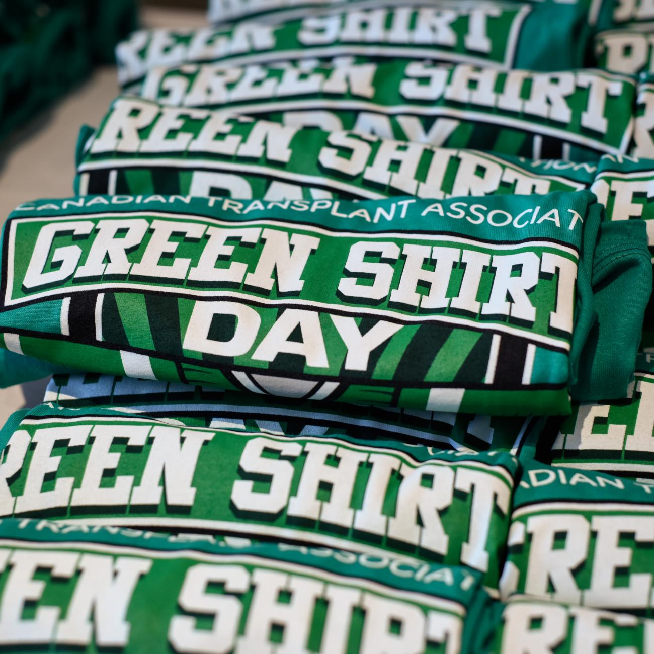 a photograph of a pile of green Green Shirt Day t-shirts on a table.