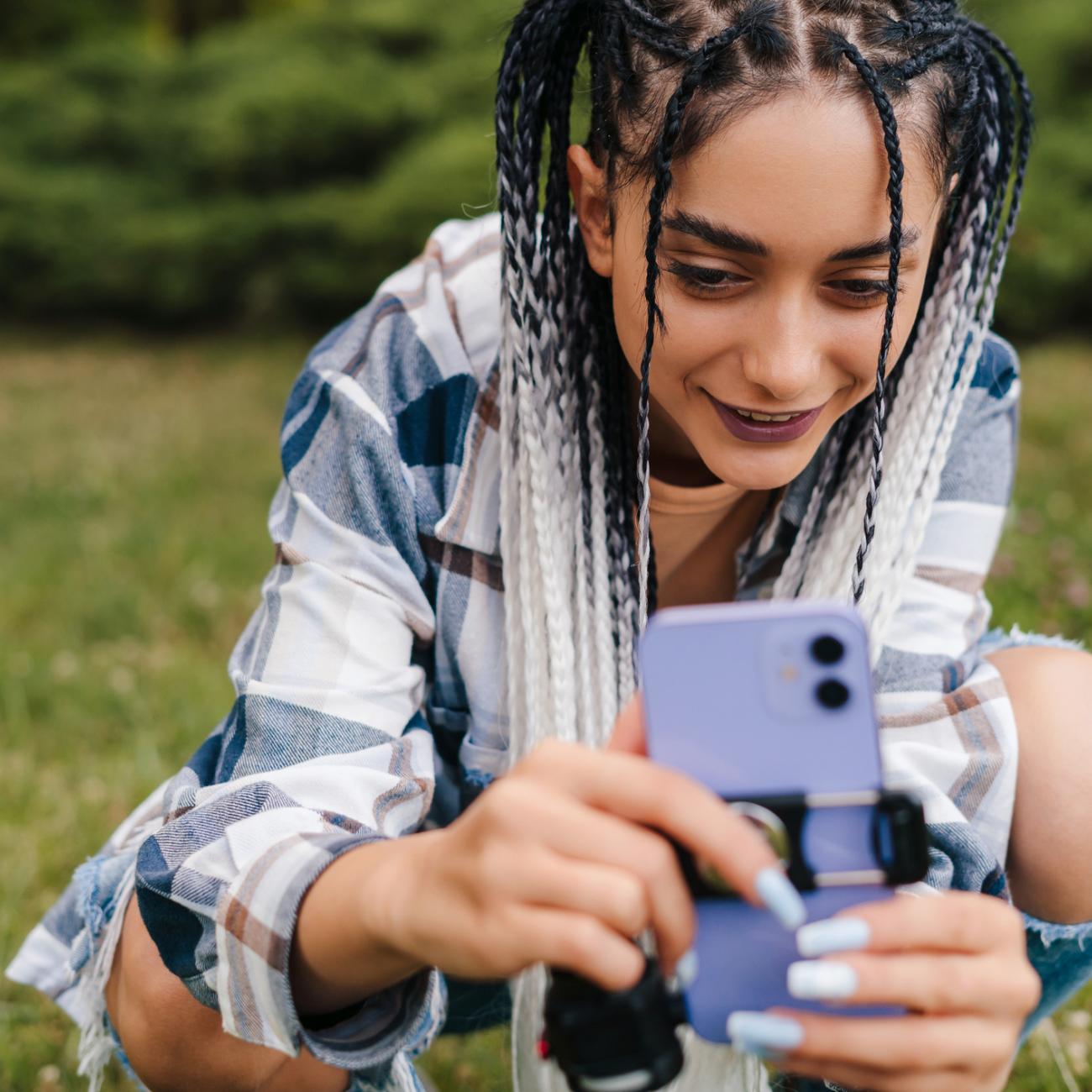 A young person crouching down using a mobile phone to capture a video